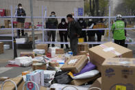 Residents wait for their deliveries behind shelves outside a community in Beijing, Thursday, Nov. 24, 2022. China is expanding lockdowns, including in a central city where factory workers clashed this week with police, as its number of COVID-19 cases hit a daily record. (AP Photo/Ng Han Guan)