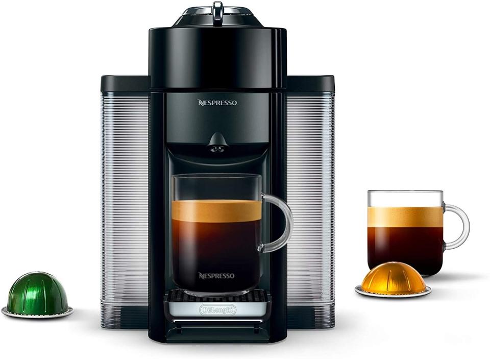 machine, capsules and mug of coffee on white background