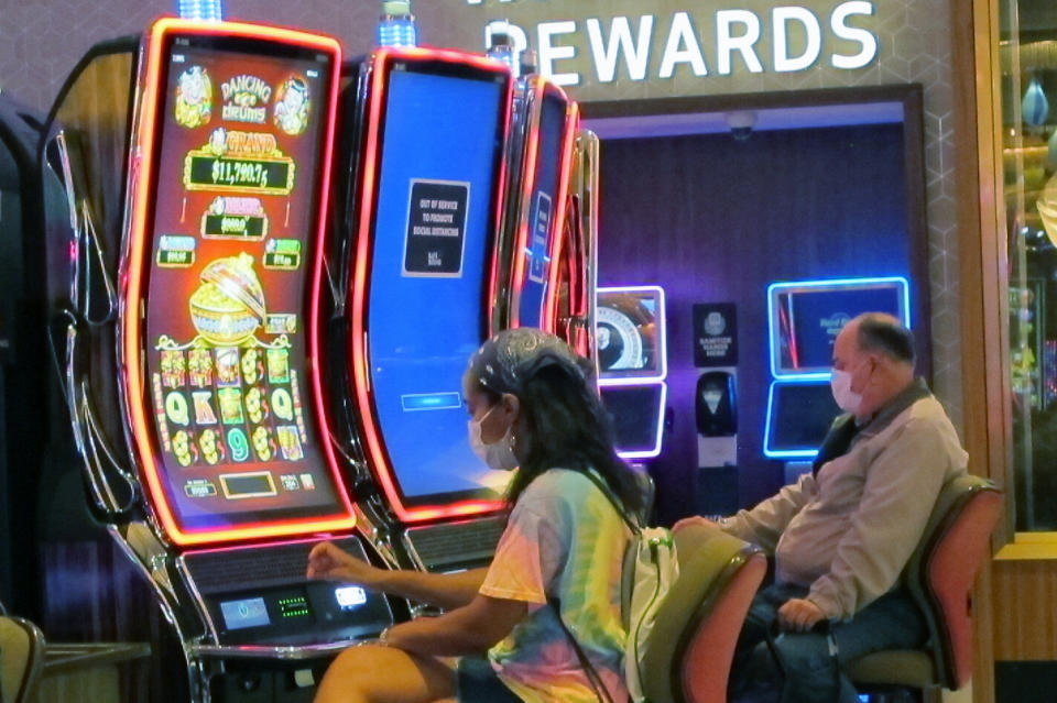 Gamblers wear face masks while playing slot machines at the Hard Rock casino in Atlantic City, N.J., on July 2, 2020, the first day it reopened after being closed for four months due to the coronavirus outbreak. American Gaming Association President Bill Miller said Tuesday, Oct. 27, 2020, the industry is adapting to the pandemic but needs assistance from the government for its casinos and workers. (AP Photo/Wayne Parry)