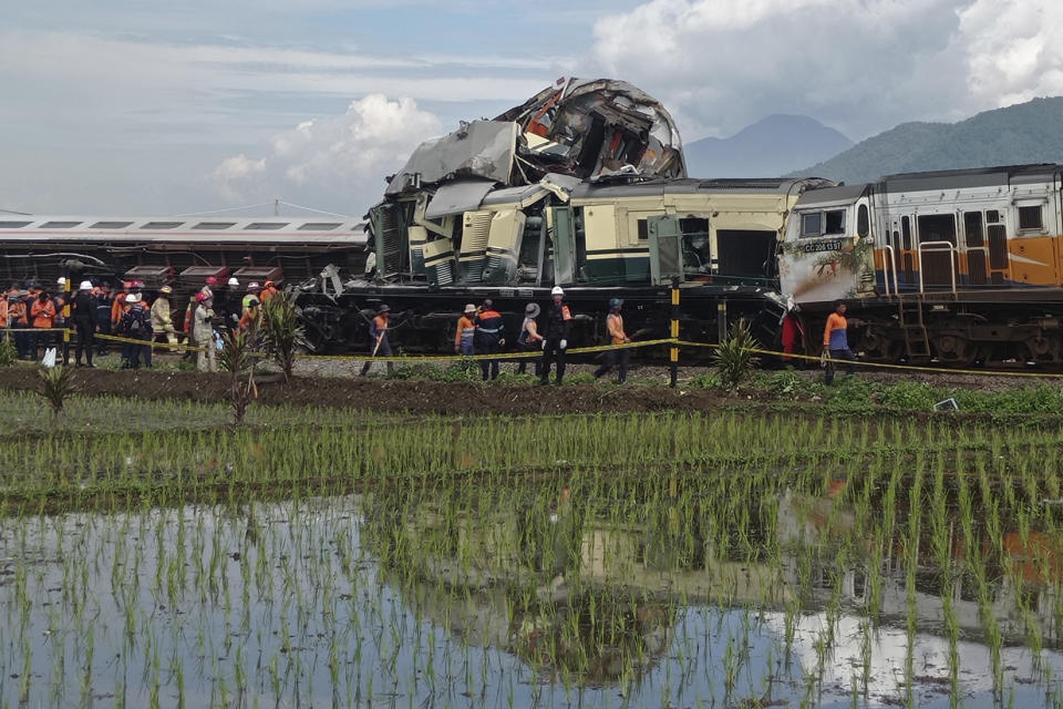 Rescuers walk near the wreckage of trains after a collision in Cicalengka, West Java, Indonesia, Friday, Jan. 5, 2024. The two trains collided on Indonesia's main island of Java on Friday, causing several carriages to buckle and overturn, officials said. (AP Photo/Abdan Syakura)