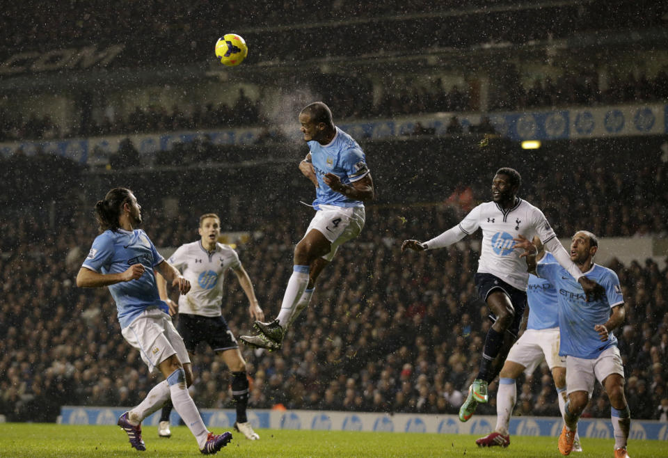 Manchester City's Vincent Kompany, center, clears the ball away during the English Premier League soccer match between Tottenham Hotspur and Manchester City at White Hart Lane stadium in London, Wednesday, Jan. 29, 2014. (AP Photo/Matt Dunham)