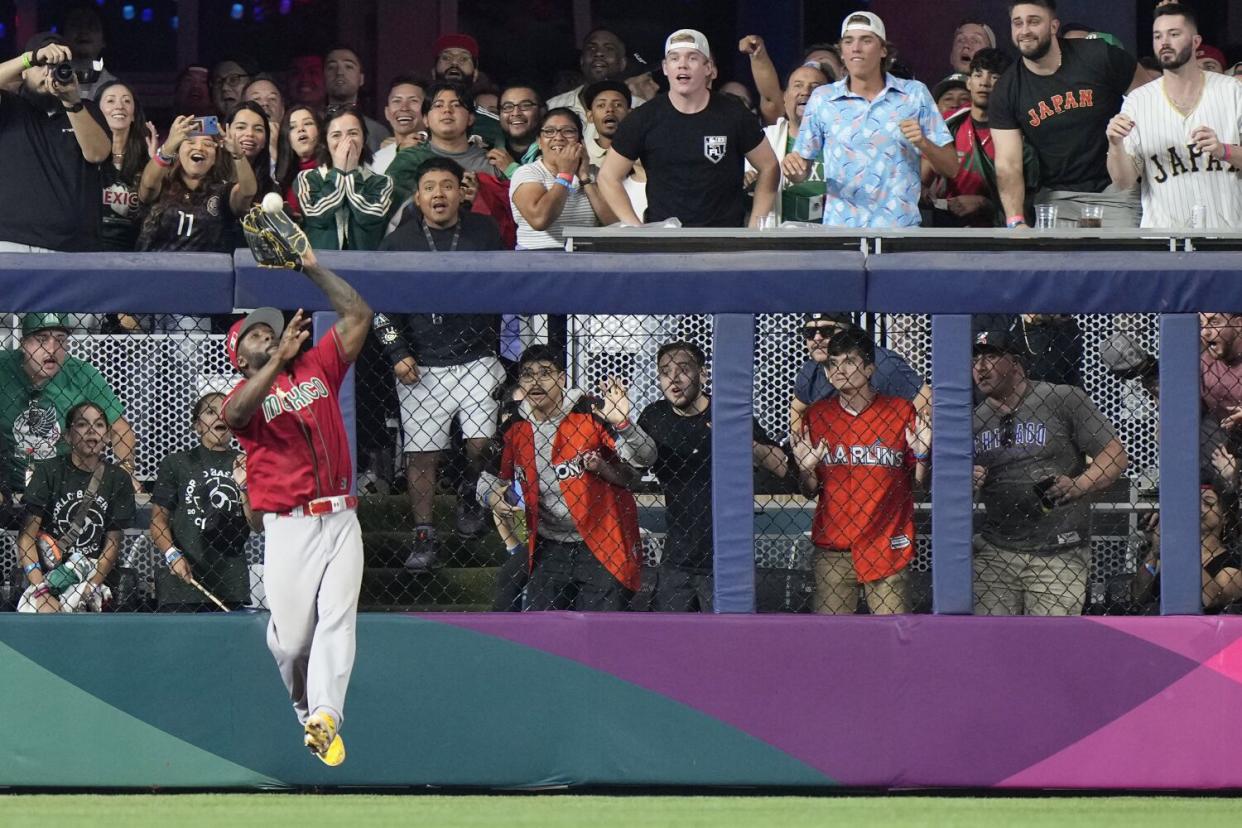 Mexico left fielder Randy Arozarena catches a ball hit by Japan's Kensuke Kondoh.