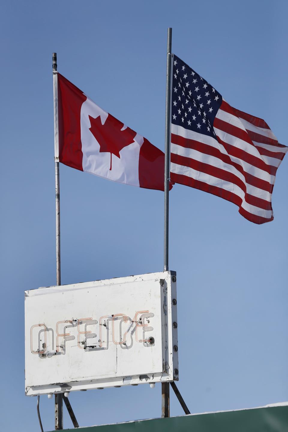 FILE- In this Feb. 9, 2017, file photo, an American flag and a Canadian flag fly above Maple Leaf Motel's office in Emerson, Manitoba. America’s neighbor to the north is increasingly being seen as a haven for asylum seekers turned away by the U.S. And some are willing to risk a walk across the border in dangerous cold to get there. (John Woods/The Canadian Press via AP, File)