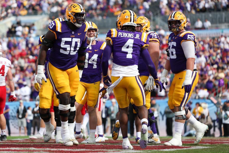 LSU Tigers offensive lineman Emery Jones Jr. (50) celebrates with LSU Tigers linebacker Harold Perkins Jr. (4) after scoring a touchdown against the Wisconsin Badgers in the second quarter during the ReliaQuest Bowl at Raymond James Stadium.