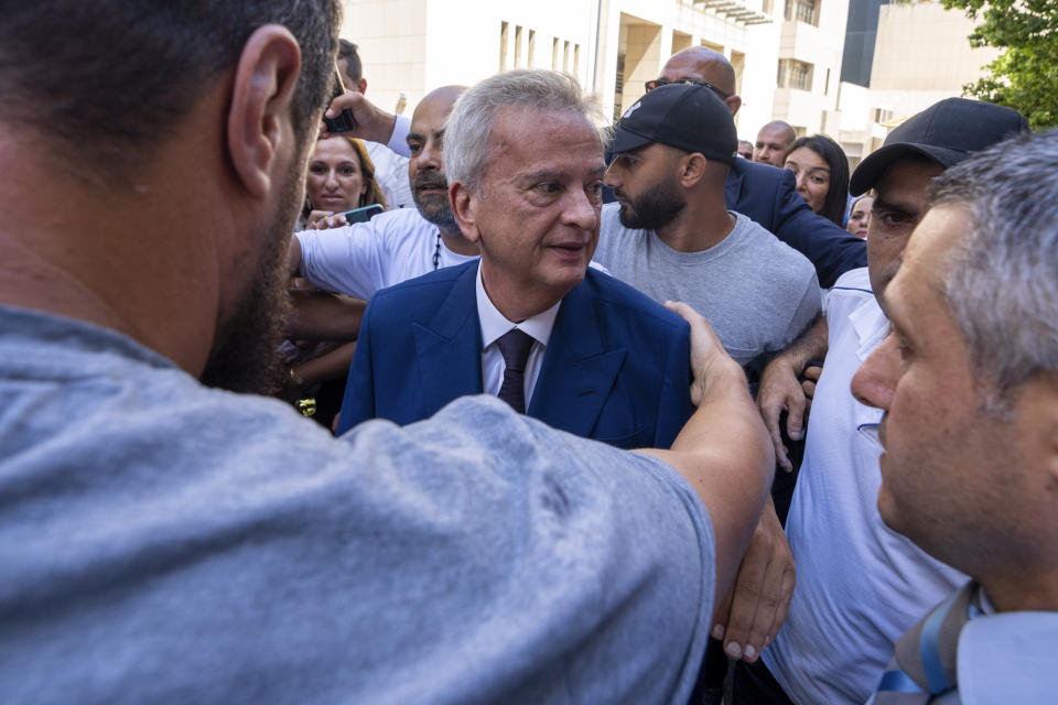 Riad Salameh, center, Lebanon's outgoing Central Bank governor, greets employees as he is escorted by bodyguards at a farewell ceremony marking the end of his 30 years in office outside the Central Bank building, in Beirut, Monday, July 31, 2023. Meanwhile, his four vice governors, led by incoming interim governor Wassim Mansouri, urged the cash-strapped country's government for fiscal reforms at a news conference in that same building. (AP Photo/Hassan Ammar)