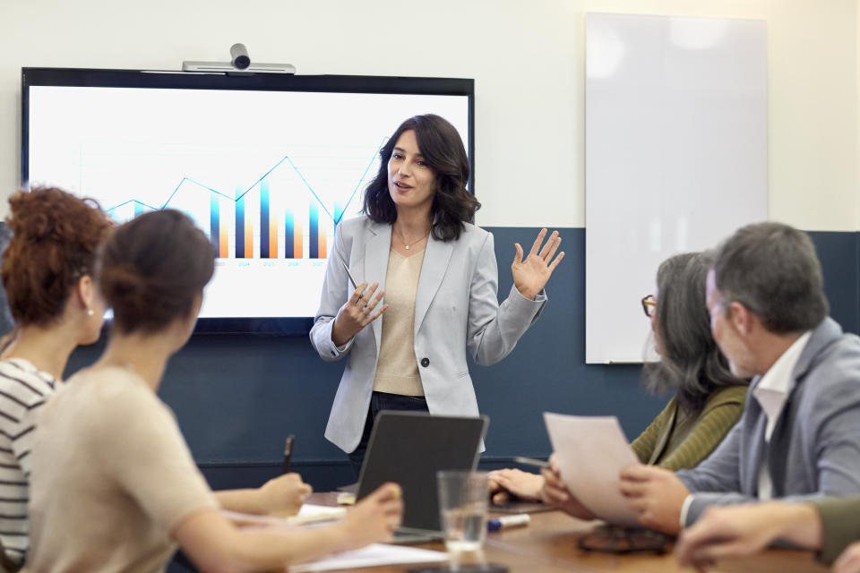 Confident businesswoman giving presentation to colleagues in board room. Entrepreneur is explaining development graph to partners. They are planning at creative office.