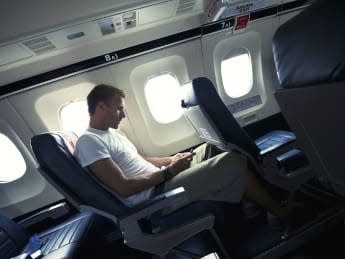 Man sits with his smartphone in the cabin of a small airplane, texting during takeoff