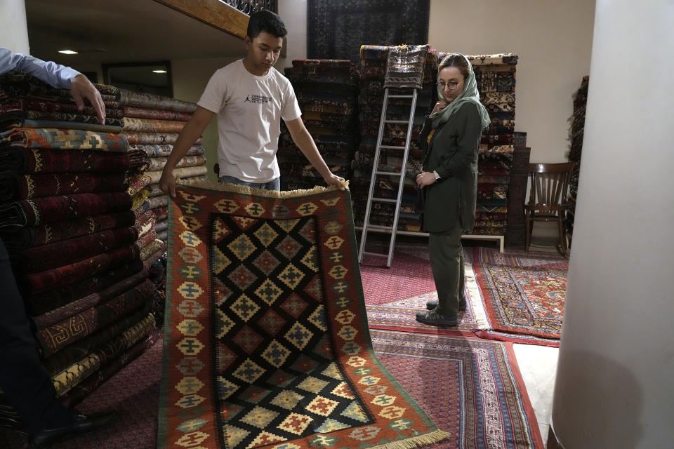 A shopkeeper shows a kilim to a customer at a carpet shop in the old main bazaar of Tehran, Iran, Thursday, June 13, 2024. The rise of the “Hamster Kombat” app in Iran highlights a harsher truth facing the Islamic Republic's economy ahead of its presidential election this week to replace the late President Ebrahim Raisi, who died in a helicopter crash in May. (AP Photo/Vahid Salemi)