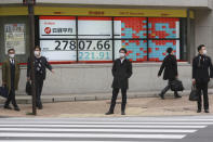 People walk by an electronic stock board of a securities firm in Tokyo, Monday, Dec. 6, 2021. Shares were mixed in Asia on Monday after troubled Chinese property developer Evergrande warned late Friday it may run out of money. (AP Photo/Koji Sasahara)