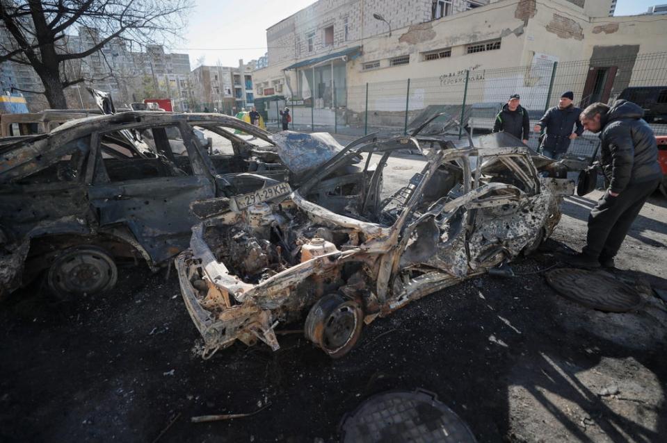 People walk past burned cars a day after a shelling on a residential area in Kyiv (EPA)