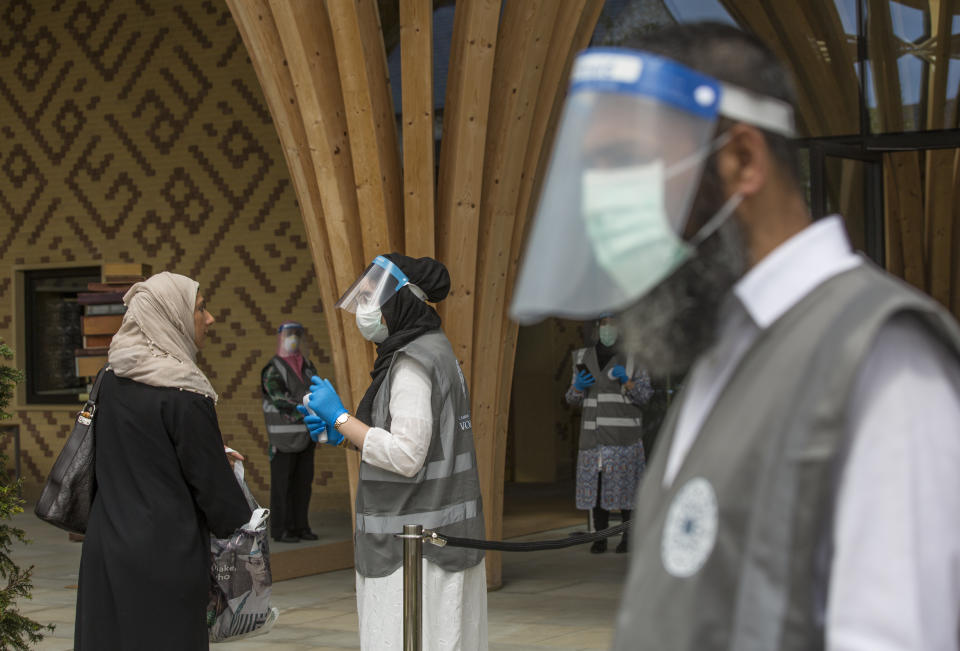 Voluntarios y personal de la Mezquita Central de Cambridge, Inglaterra, reciben a los feligreses en el primer oficio de los viernes desde la cuarentena, 10 de julio de 2020. (AP Foto/Elizabeth Dalziel)