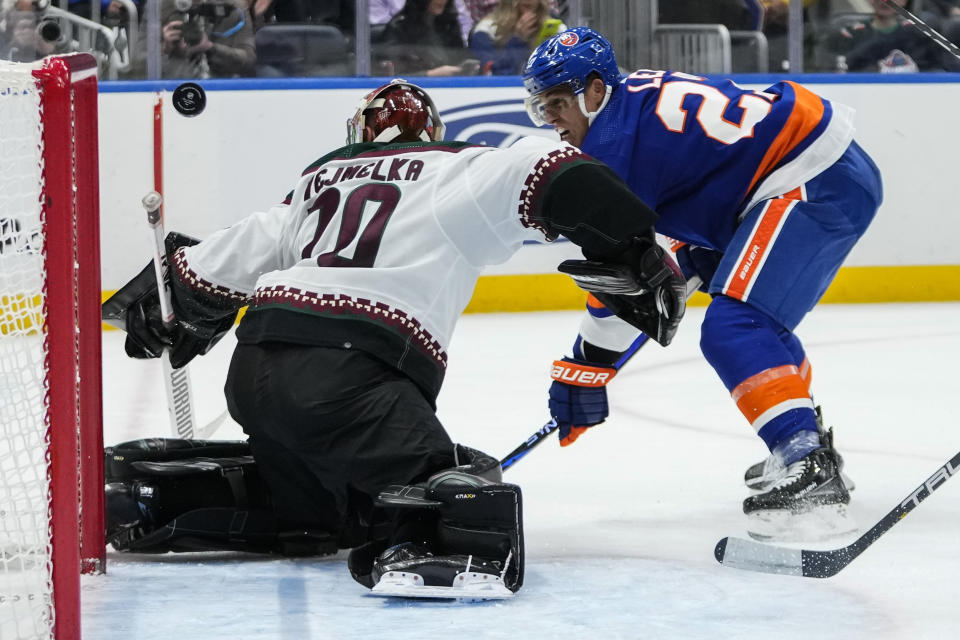 Arizona Coyotes goaltender Karel Vejmelka, left, stops a shot on goal by New York Islanders' Anders Lee during the second period of an NHL hockey game Tuesday, Oct. 17, 2023, in Elmont, N.Y. (AP Photo/Frank Franklin II)