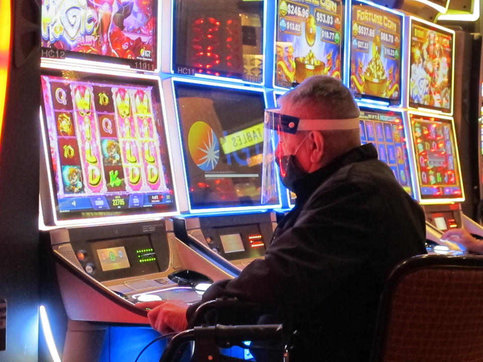 In this July 2, 2020 photo, a man plays a slot machine at the Golden Nugget casino in Atlantic City N.J. Gambling companies in the U.S. are increasingly bringing different forms of gambling together, including sports betting, casino gambling, internet gambling and daily fantasy sports, and partnering with media companies as they seek to increase revenue. (AP Photo/Wayne Parry)