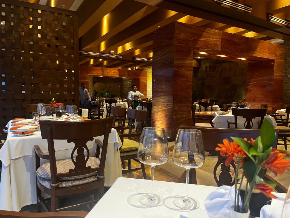 Interior of an upscale restaurant with wooden details and wine glasses and orange flowers on table