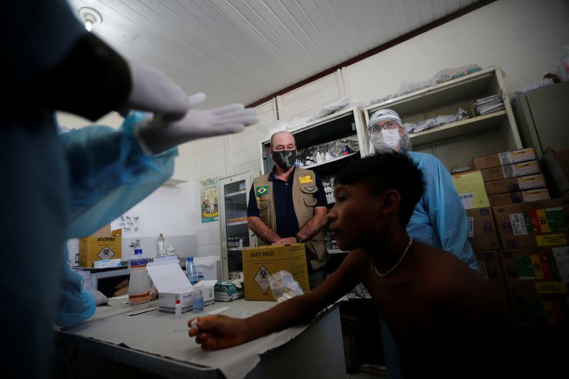 Brazil's Defense Minister Fernando Azevedo e Silva is seen as a member of Brazilian Armed Forces medical team examines a boy at the 4th Surucucu Special Frontier Platoon of the Brazilian army in the municipality of Alto Alegre