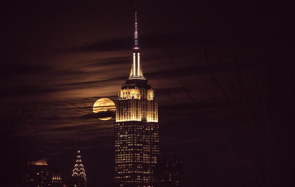 NEW YORK, USA - JANUARY 31: The Empire State building is seen as a full moon rises behind the building in New York, United States on January 31, 2018. The 'Super Blue Blood Moon' is a rare 'lunar trifecta' event in which the moon is at its closest to the earth, appearing bigger and brighter than usual and is simultaneously a 'blue moon', the second full moon in the same month, and in total lunar eclipse or 'blood moon'. For the first time in 152 years, a super moon, blue moon, and total lunar eclipse coincide. (Photo by Atilgan Ozdil/Anadolu Agency/Getty Images)