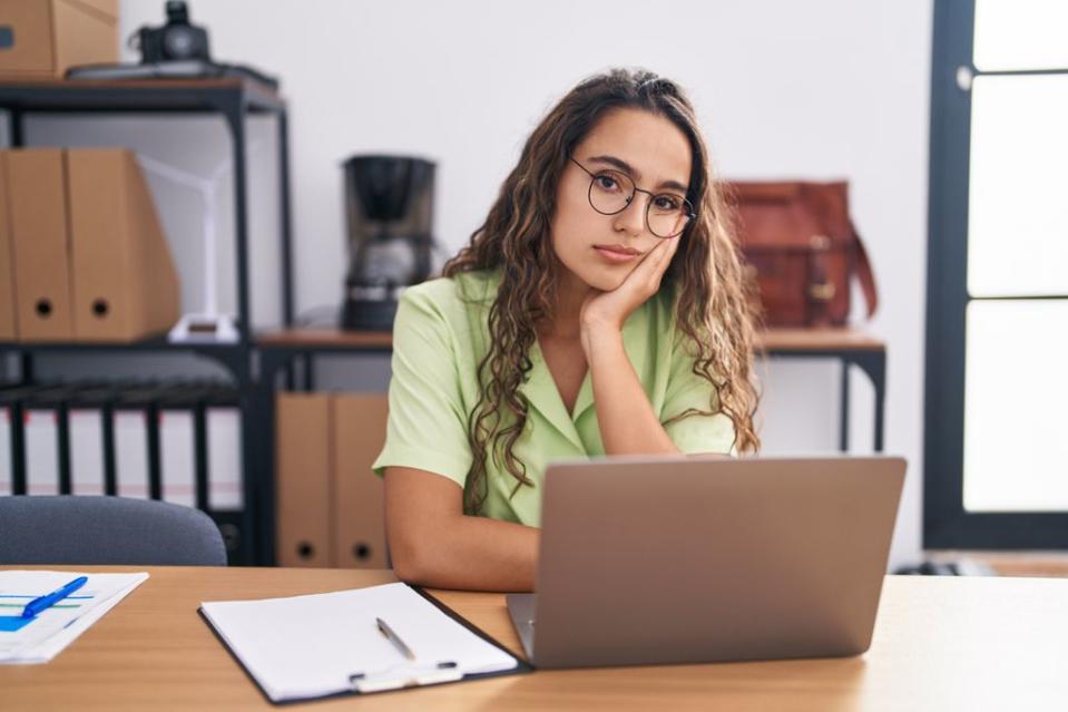 mujer con gafas frente a su ordenador portátil