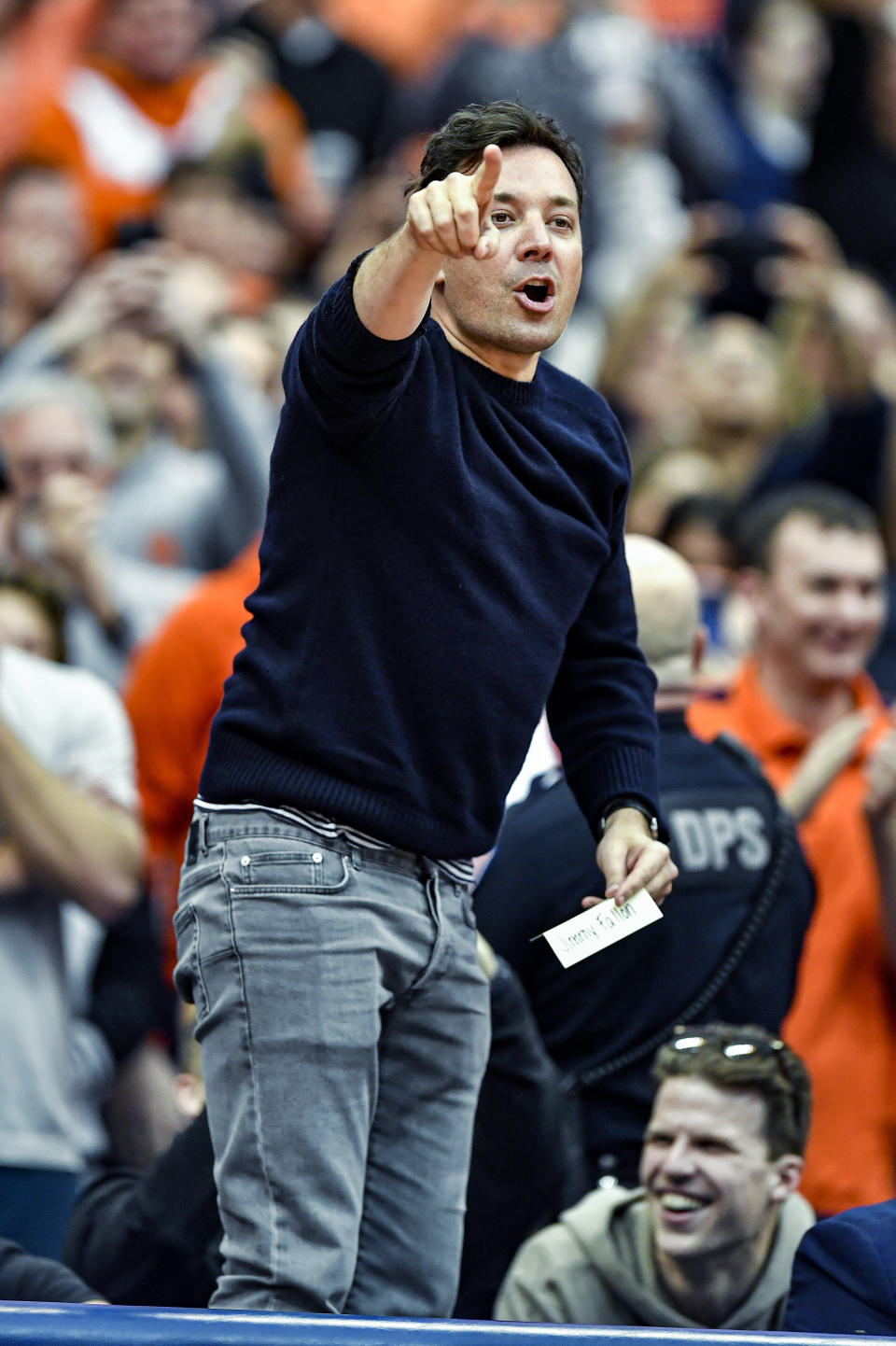 Jimmy Fallon stands on his chair as he is introduced to the crowd during the first half of an NCAA college basketball game between Syracuse and North Carolina in Syracuse, N.Y., Saturday, Feb. 29, 2020. (AP Photo/Adrian Kraus)