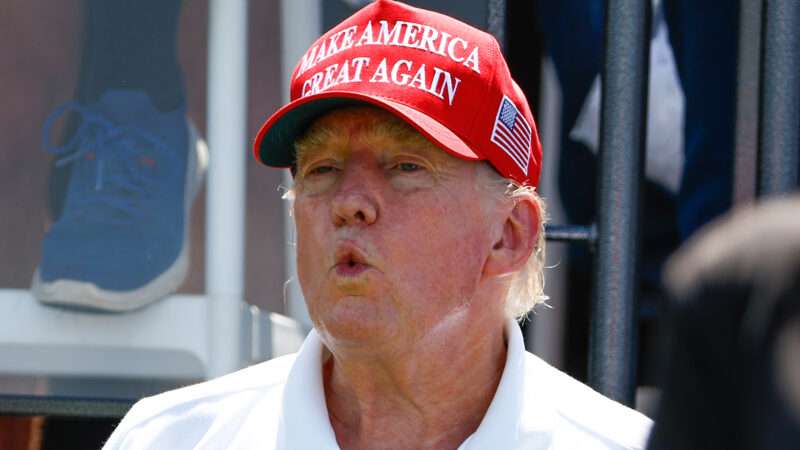 Donald Trump wears a white polo and a Make America Great Again hat