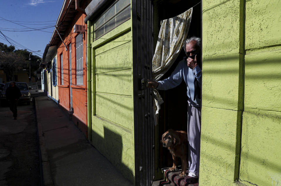 Carlos Gonzalez, 78, watches from his home as city workers deliver boxes of food during a mandatory quarantine ordered by the government amid the new coronavirus pandemic in Santiago, Friday, May 22, 2020. The Chilean government began delivery of 2.5 million boxes of food and cleaning products for vulnerable families. (AP Photo/Esteban Felix)