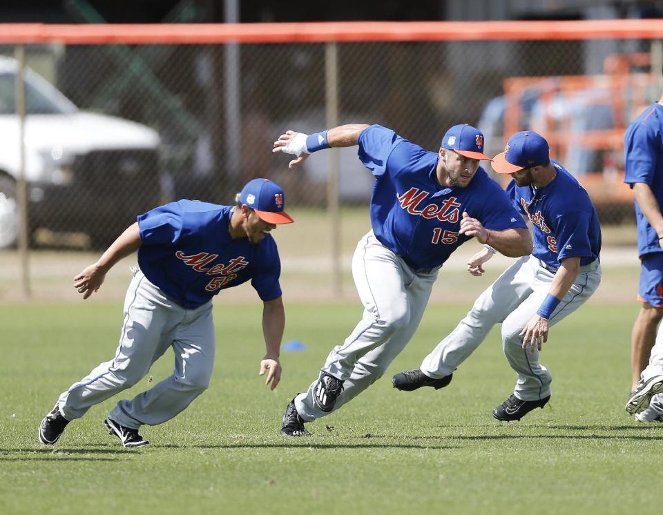 Former NFL quarterback and New York Mets outfielder Tim Tebow (15), center, works during a spring training baseball practice Monday, Feb. 27, 2017, in Port St. Lucie, Fla. (AP Photo/John Bazemore)