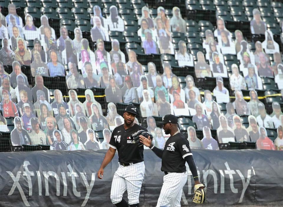 <p>Eloy Jimenez #74 (L) and Luis Robert #88 of the Chicago White Sox celebrate an inning-ending catch in front of "cut-out" fans during an exhibition game against the Milwaukee Brewers at Guaranteed Rate Field on July 22 in Chicago.</p>