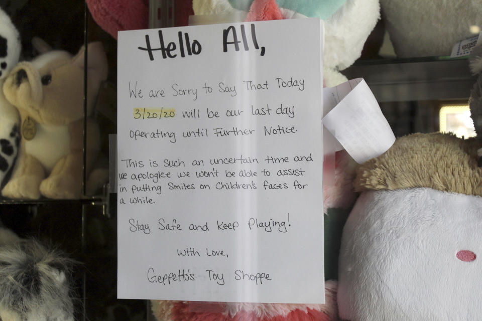 In this Thursday, May 28, 2020, photo, a sign announcing the closure of Gepetto's Toy Shop due to the coronavirus is displayed in Cannon Beach, Ore. With summer looming, Cannon Beach and thousands of other small, tourist-dependent towns nationwide are struggling to balance fears of contagion with their economic survival in what could be a make-or-break summer. (AP Photo/Gillian Flaccus)