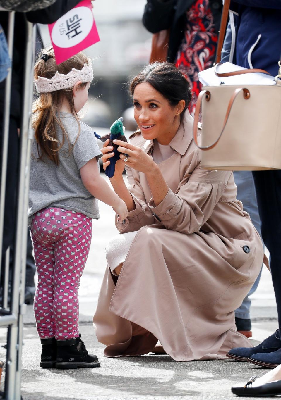 Meghan kneeled down to talk to a little girl and play with a stuffed animal bird during an outing in Auckland, New Zealand.