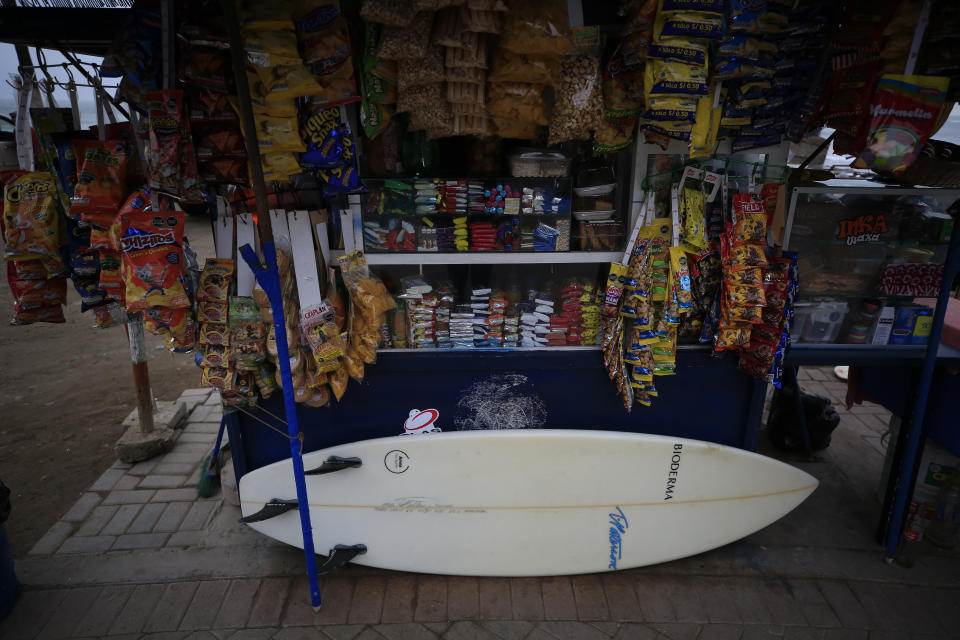 A surfboard leans against the front of a food stall, at Barranquito beach in Lima, Peru, Thursday, July 25, 2019. Today, dozens of schools teach tourists from across the world how to ride waves at beaches with Hawaiian names in Lima's Miraflores district, while professional surfers from across the Americas prepare to compete when the sport is featured for the first time in the Pan American Games in the Peruvian capital.(AP Photo/Rebecca Blackwell)