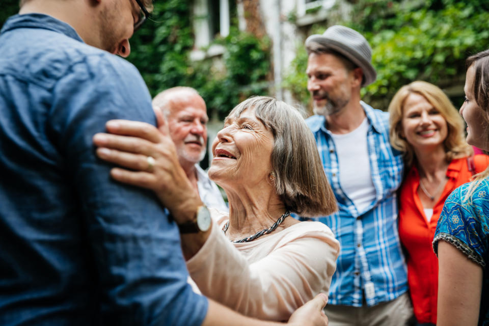 older woman smiling and grabbing a younger man by the shoulders