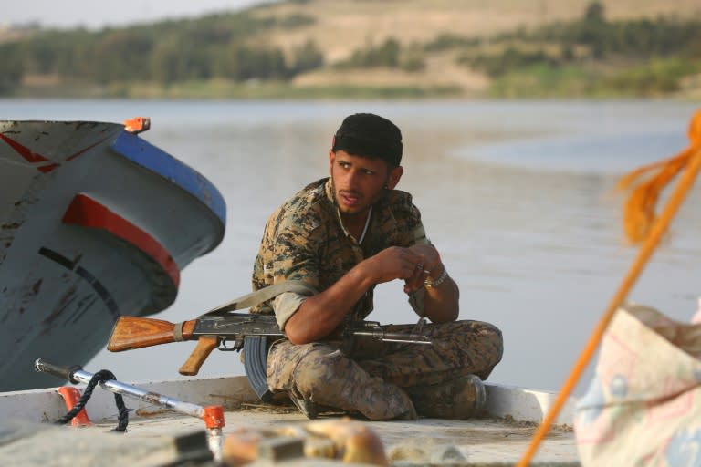 A member of the US-backed Syrian Democratic Forces (SDF) sits on the edge of a boat at Lake Assad on April 29, 2017