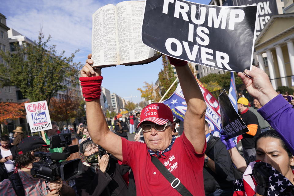 A supporter of President Donald Trump holds a Bible as people gather on a section of 16th Street renamed Black Lives Matter Plaza, Friday Nov. 13, 2020, in Washington. (AP Photo/Jacquelyn Martin)