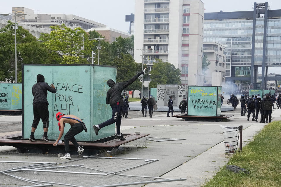 FILE - Youth throws a bottle to police forces during riots Thursday, June 29, 2023 in Nanterre, outside Paris. In all, more than 3,600 people have been detained in the unrest across France since the death of Nahel on June 27, with an average age of 17, according to the Interior Ministry. The violence left more than 800 law enforcement officers injured, French courts are working overtime to process the arrests, including opening their doors through the weekend, with fast-track hearings around an hour long and same-day sentencing. (AP Photo/Michel Euler, File)