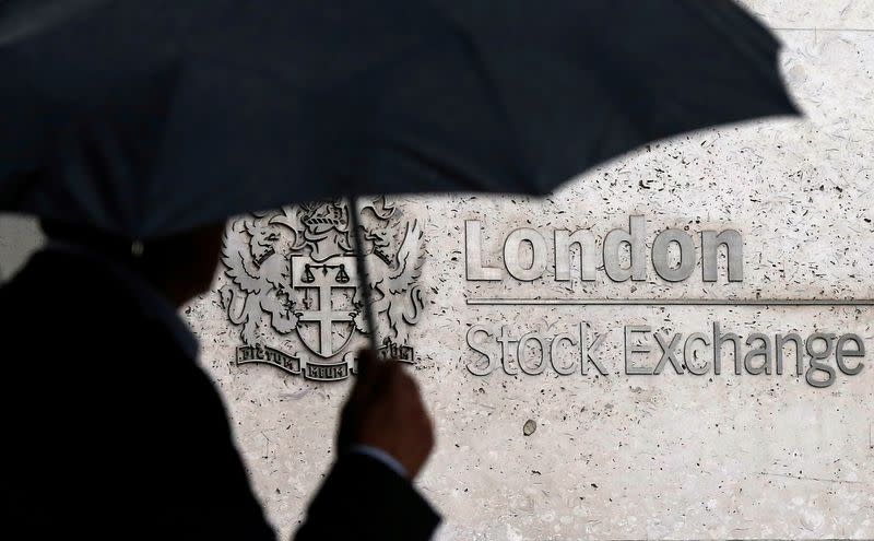FILE PHOTO: FILE PHOTO: A man shelters under an umbrella as he walks past the London Stock Exchange