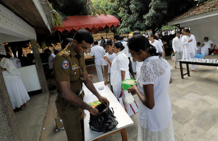 Police officers search the bags of the worshipers at an entrance of the Kelaniya Buddhist temple during Vesak Day, commemorating the birth, enlightenment and death of Buddha, in Colombo, Sri Lanka May 18, 2019. REUTERS/Dinuka Liyanawatte