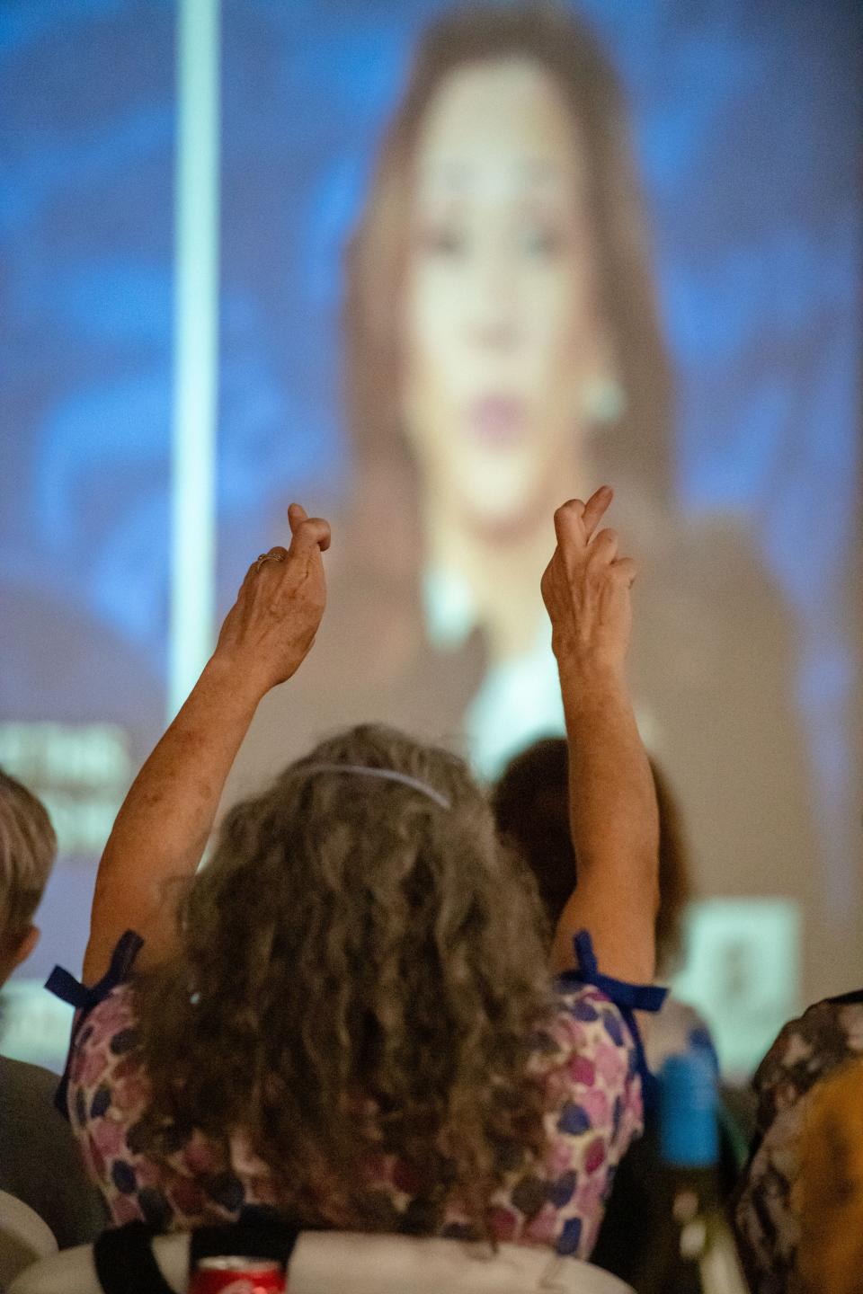 Deborah Groening raises crossed fingers into the air while watching the presidential debate between Vice President Kamala Harris and former President Donald Trump at the Buncombe County Democratic Party headquarters, September 10, 2024.