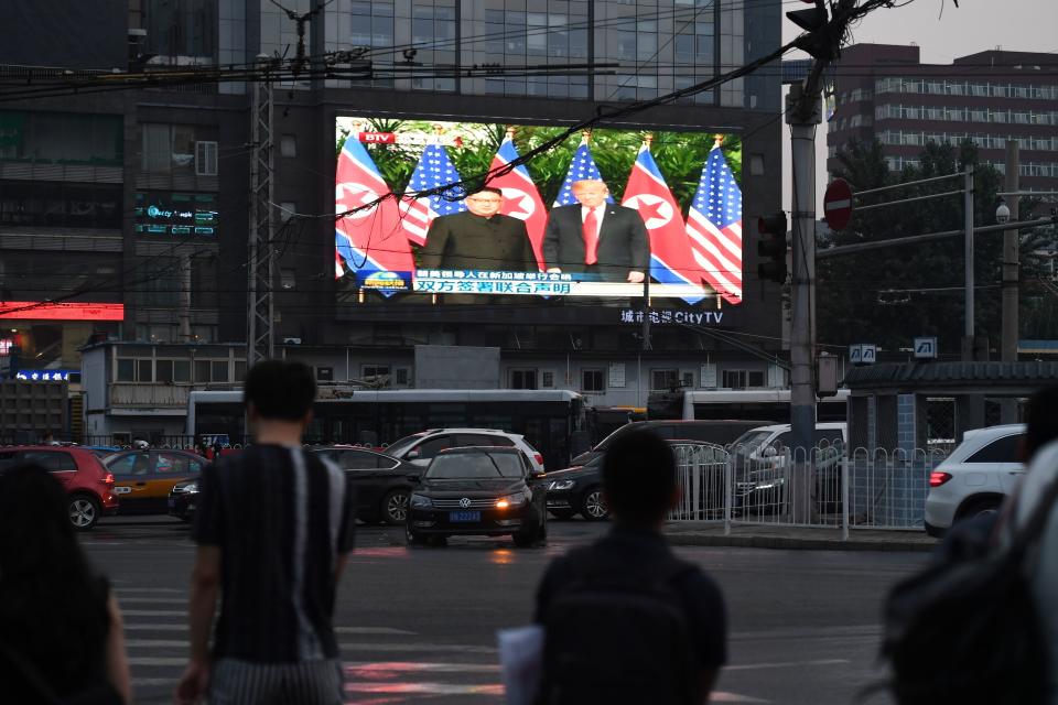 <p>A large outdoor screen shows news footage of the summit meeting in Singapore between President Trump and North Korean leader Kim Jong Un on Tuesday. (Photo: Greg Baker/AFP/Getty Images) </p>