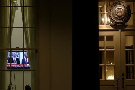 A television plays a news report on U.S. President Donald Trump's recent Oval Office meeting with Russia's Foreign Minister Sergei Lavrov as night falls on offices and the entrance of the West Wing White House in Washington, U.S. May 15, 2017. REUTERS/Jonathan Ernst