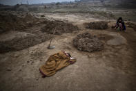 <p>Pakistani boy, Adil Shahid, 6, suffering from a fever, sleeps on the ground wrapped with a shawl, next to his mother Najma, 25, at the site of her work in a brick factory in Mandra, near Rawalpindi, Pakistan, March 3, 2014. (Photo: Muhammed Muheisen/AP) </p>