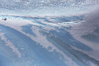 <p>The shadow of NASA’s Operation IceBridge research aircraft (left) is cast over blue ice, in the Antarctic Peninsula region, on Oct. 31, 2017, above Antarctica. (Photo: Mario Tama/Getty Images) </p>