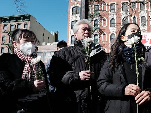 A picture of people holding white flowers at a vigil for Christina Yuna Lee.