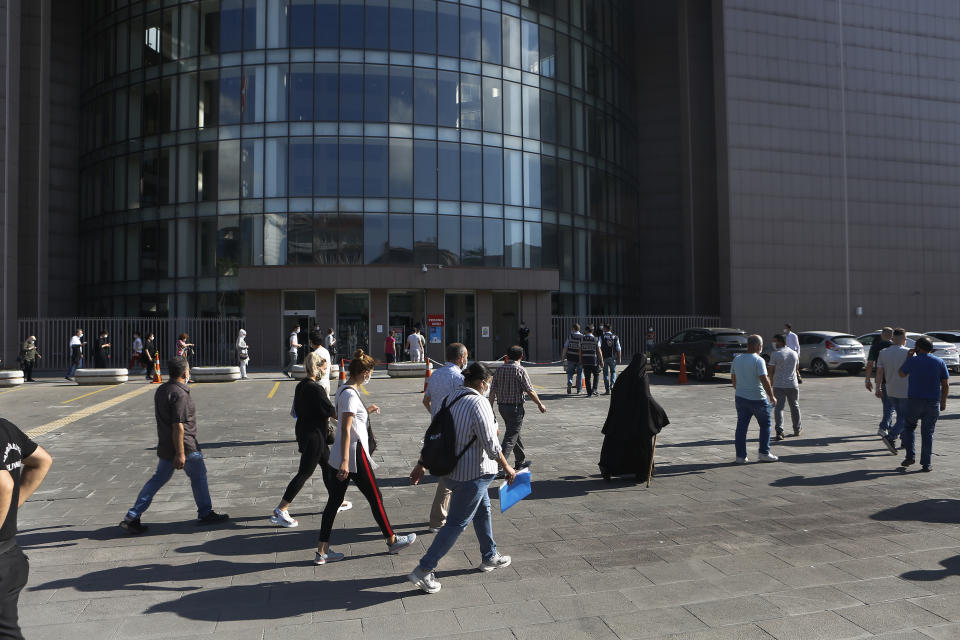 People walk outside a court in Istanbul, Friday, July 3, 2020, where the trial began for defendants accused of smuggling former Nissan Motor Co. chairman Carlos Ghosn out of Japan. A private airline official, four pilots and two flights attendants are on trial in Istanbul, accused of smuggling former Nissan Motor Co. chairman Carlos Ghosn out of Japan to Lebanon, via Turkey. Turkish prosecutors are seeking up to eight years in prison each for the four pilots and the airline official on charges of illegally smuggling a migrant, for helping Ghosn escape to Lebanon while he awaited trial in Japan. (AP Photo/Mehmet Guzel)