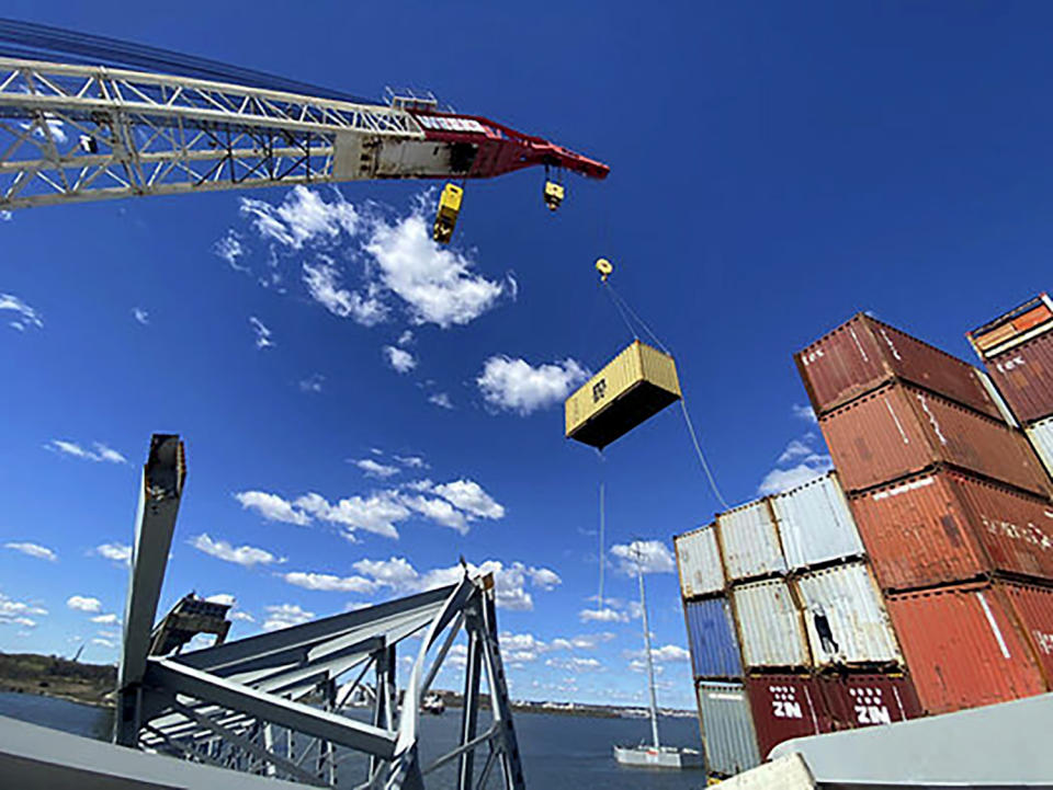 In this photo provided by the Key Bridge Response 2024 Unified Command, response crews begin removing shipping containers from the deck of the cargo ship Dali using a floating crane barge at the site of the Francis Scott Key Bridge, Sunday, April 7, 2024, in Baltimore. (Key Bridge Response 2024 Unified Command via AP)