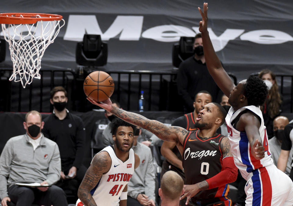 Portland Trail Blazers guard Damian Lillard (0) drives to the basket on Detroit Pistons forward Sekou Doumbouya, right, during the first half of an NBA basketball game in Portland, Ore., Saturday, April 10, 2021. (AP Photo/Steve Dykes)