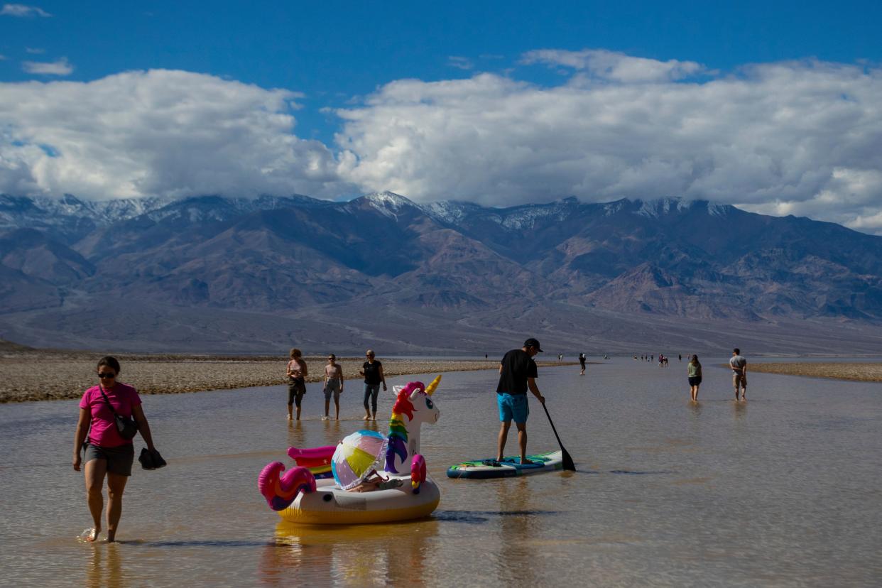 A paddle boarder tows an inflatable unicorn Thursday on a temporary lake in Death Valley National Park. A series of storms have brought more than double the California park's annual rainfall in the past six months.