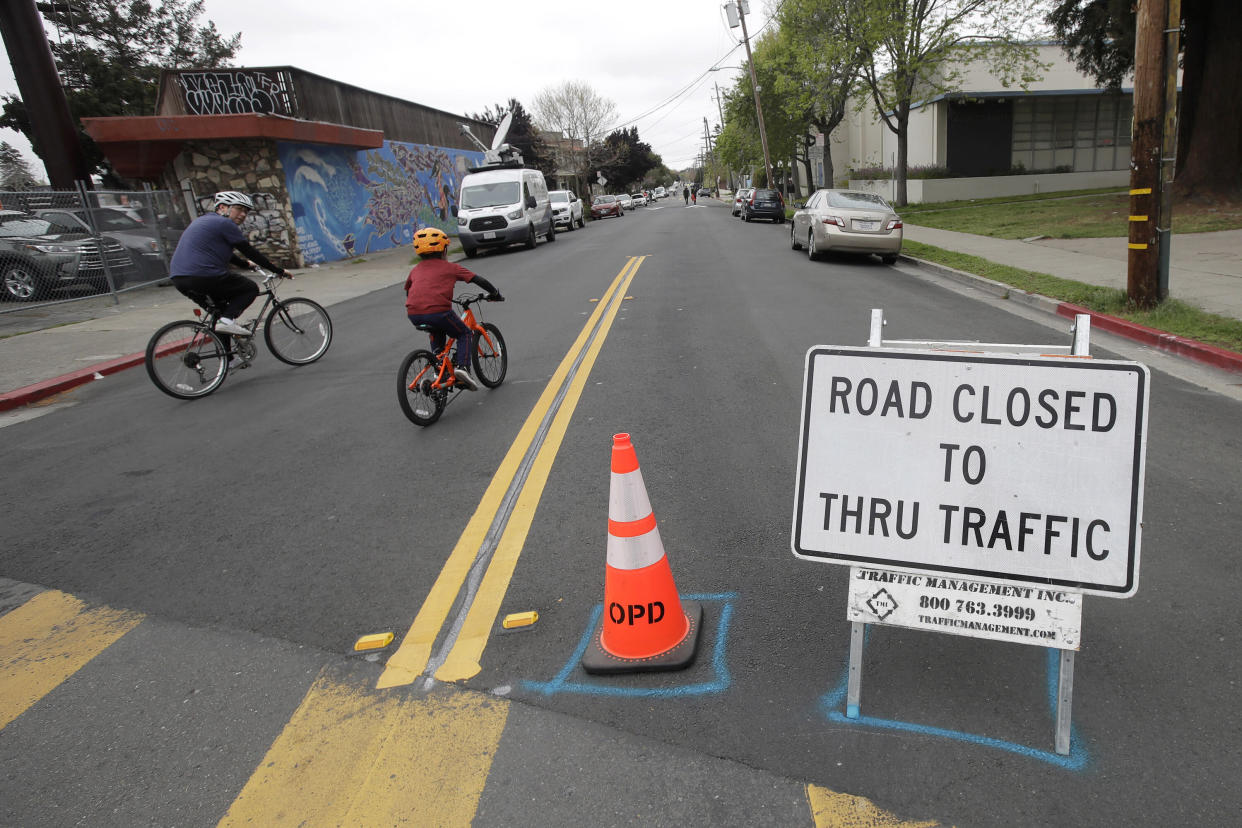 A man and child ride bicycles on a street closed to traffic in Oakland, California, on April 11, 2020. All around the country and the world, bicycles are selling out and officials are trying to take advantage of the growing momentum by expanding bike lanes during the coronavirus pandemic.  (Photo: AP Photo/Jeff Chiu, File)