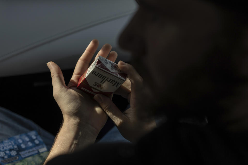 Tyler Baker packs his cigarettes as he talks with his peer support worker Jesse Johnson of the Family Resource Center after she drove him to take a random drug test at the Hancock County Adult Probation office in Findlay, Ohio, Thursday, Oct. 12, 2023. Peer support services are one key element of Hancock County's response to an opioid epidemic that has touched every part of the U.S. (AP Photo/Carolyn Kaster)