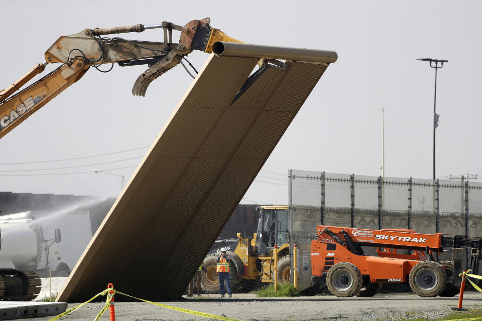 In this Feb. 27, 2019, file photo, a border wall prototype falls during demolition at the border between Tijuana, Mexico, and San Diego. The government is demolishing eight prototypes of Donald Trump's prized border wall that instantly became powerful symbols of his presidency when they were built nine months after he took office. The Biden administration says it will begin work to address flooding and soil erosion risks from unfinished walls on the U.S. border with Mexico. It also began providing answers on how it will use unspent money from shutting down one of President Donald Trump's signature domestic projects. The Defense Department says it will use unobligated money for military construction projects for its initial purpose. (AP Photo/Gregory Bull, File)