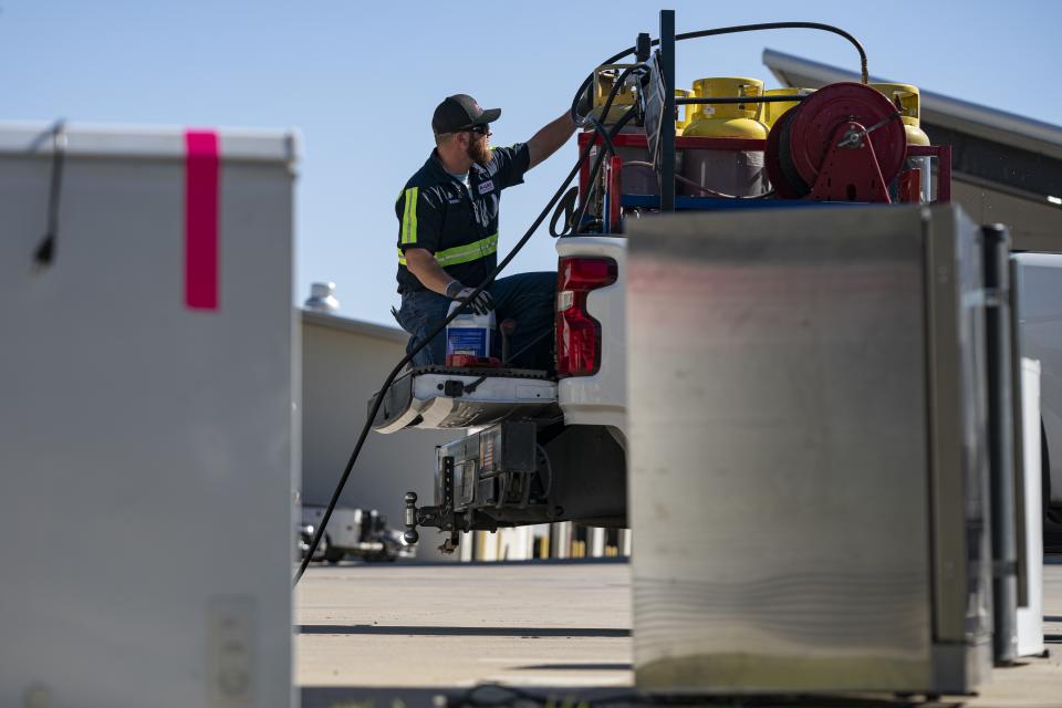 An operator prepares equipment in a truck bed at a customer recovery job site on Monday, Oct. 9, 2023, in Little Elm, Texas. The company A-Gas takes in shipments of refrigerators and tanks from around the country and beyond, drains them, then purifies and reclaims the chemicals, shipping out recycled product. This prevents the need for new chemical production. (AP Photo/Sam Hodde)