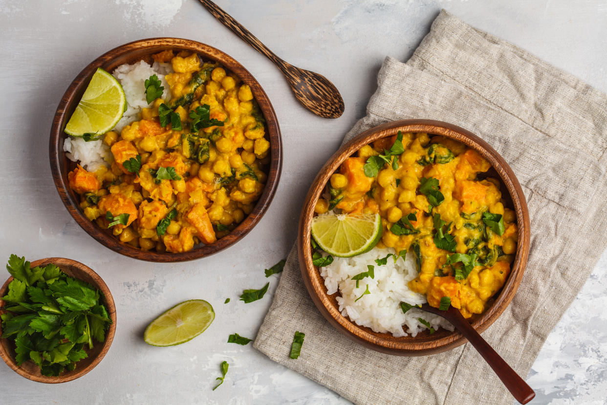 Vegan Sweet Potato Chickpea curry in wooden bowl on a light background, top view, copy space. Healthy vegetarian food concept.